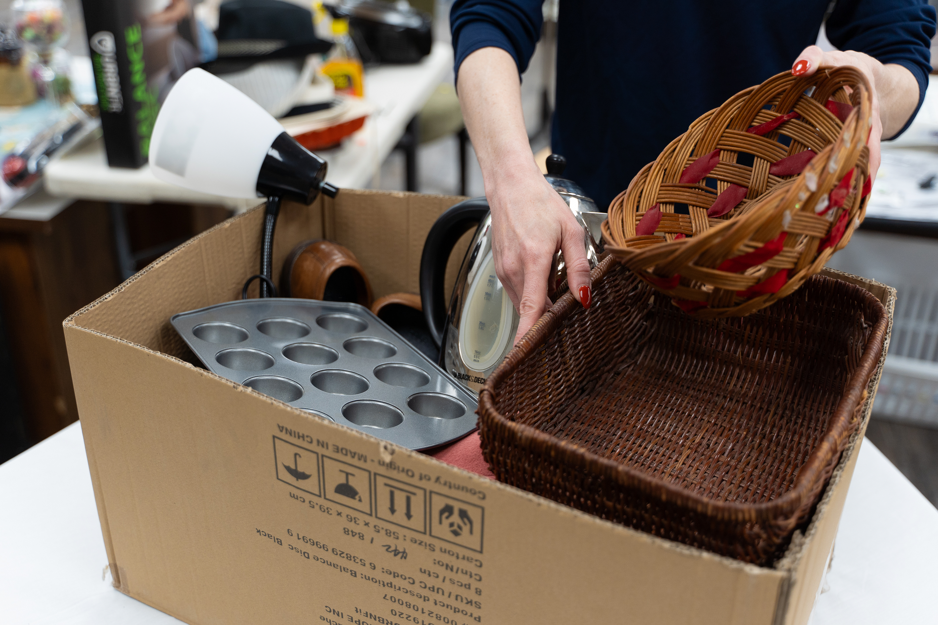 person putting household items in a box to donate