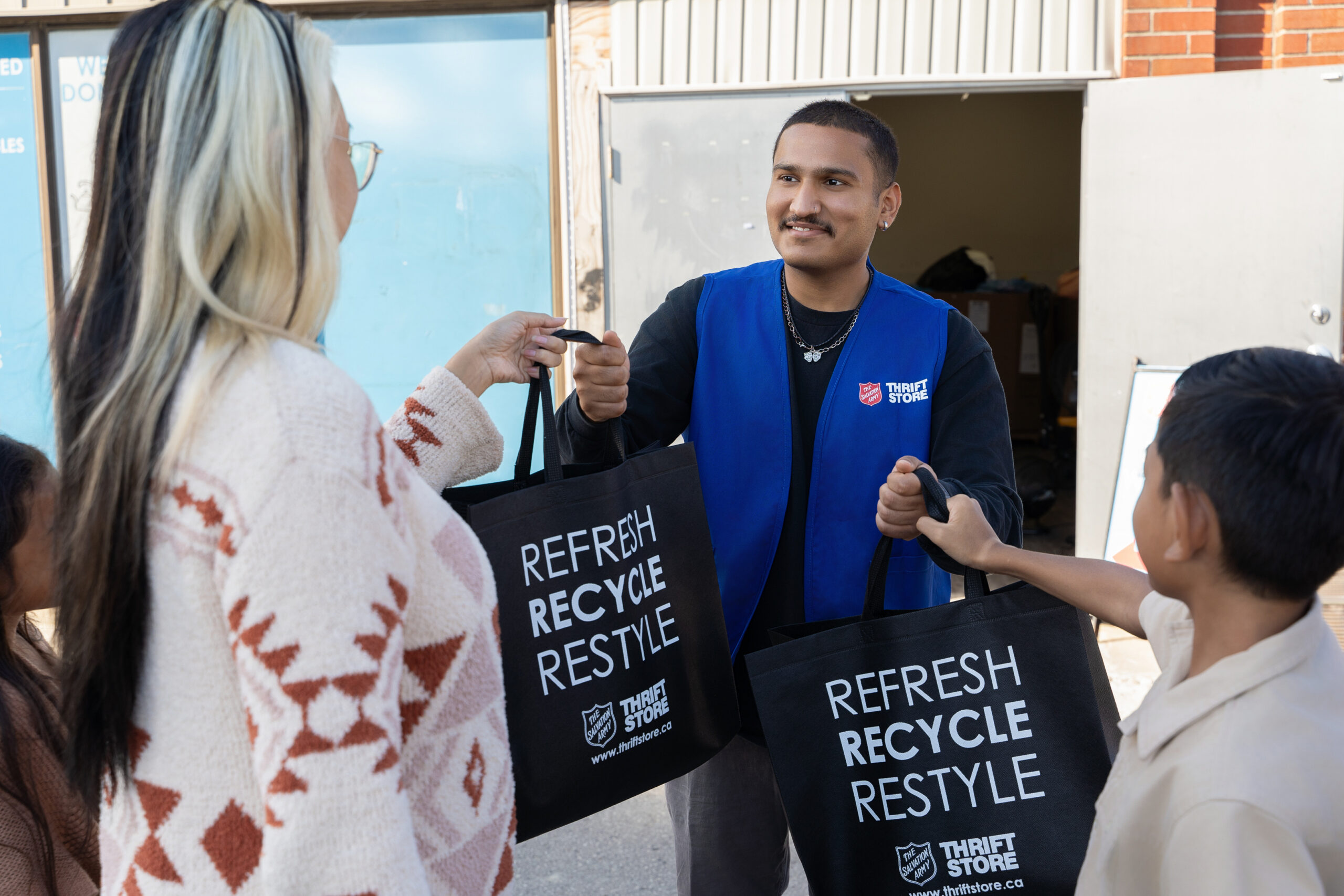 employé d’un magasin d’occasion tenant des sacs de dons de deux personnes employé d'un magasin d'occasion tenant des sacs de dons de deux personnes
