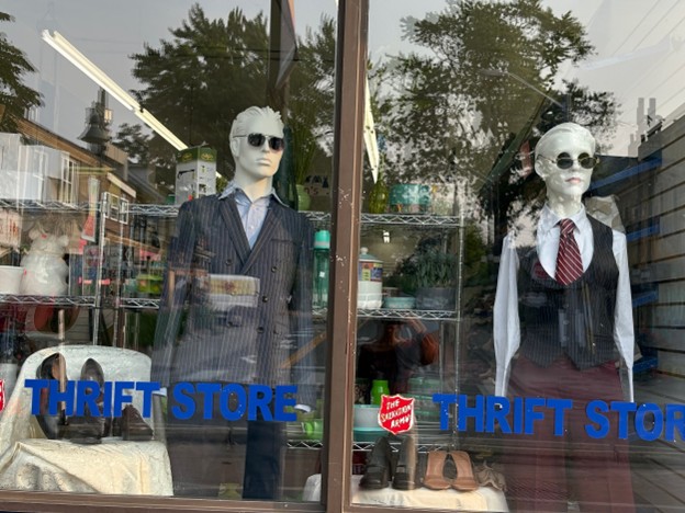 tenues de travail blazer masculin, chemise et lunettes de soleil sur un mannequin et un gilet, une cravate, un haut à col et des lunettes de soleil sur un mannequin féminin dans une vitrine