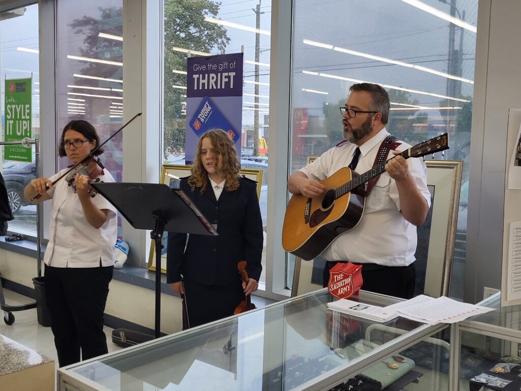 Un guitariste chantant et deux violonistes debout jouant dans une friperie avec un pupitre