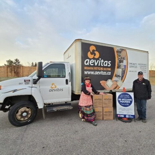 Des employés d'Aevitas se tiennent à côté d'un camion pour une collecte de dons carrée
