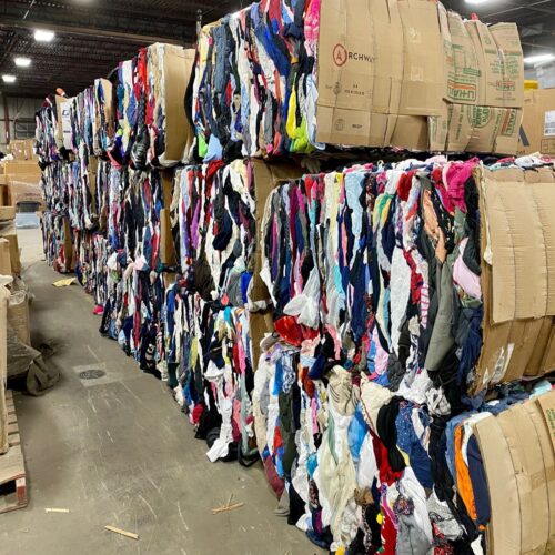 Des ballots de carton remplis de vêtements empilés les uns sur les autres dans un entrepôt