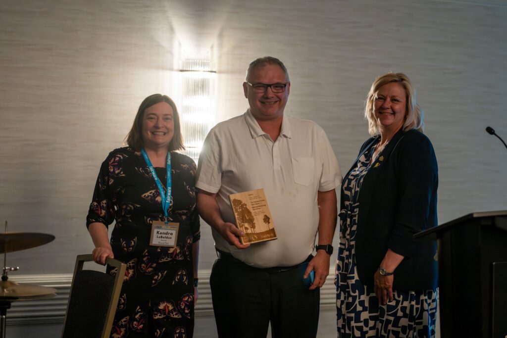3 people smiling holding the SK Waste Reduction Award