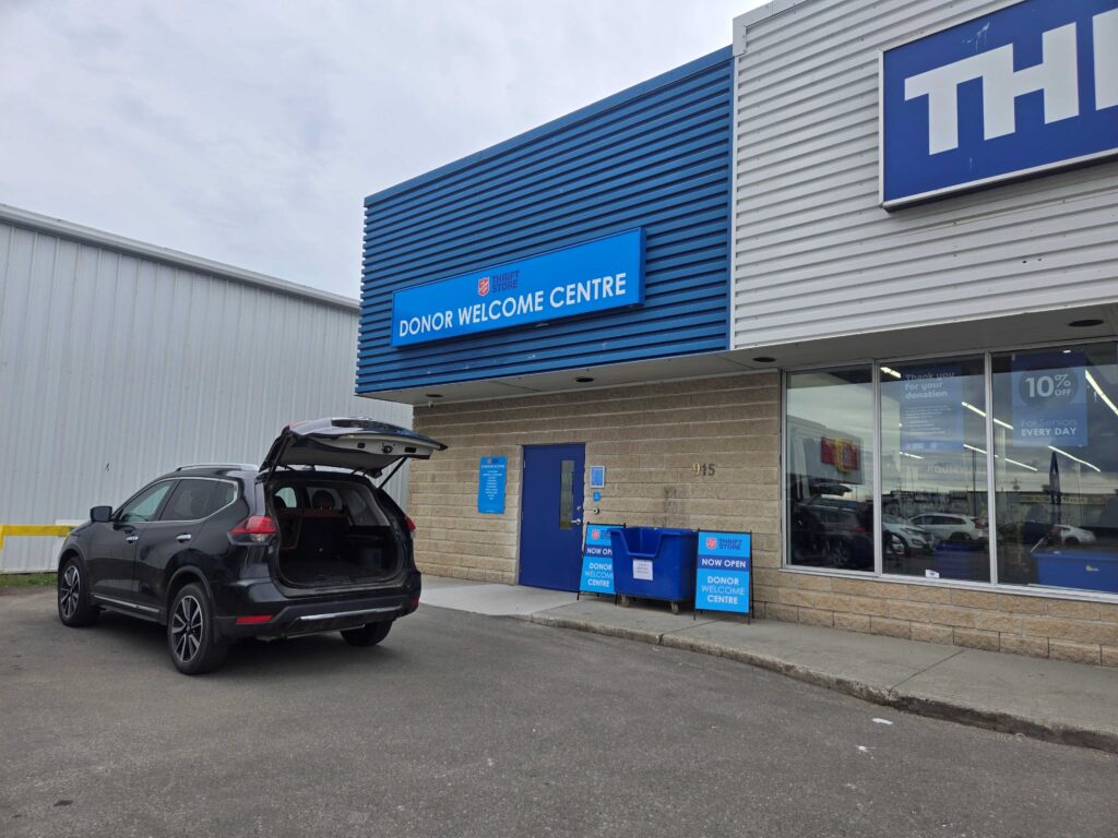 Voiture noire devant le magasin de l'Armée du Salut, coffre ouvert.