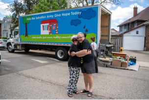 2 members of community hugging in front of Salvation Army vehicle